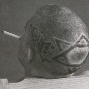 A black and white image of the back of a shaved head. There is the pattern of a star of David on the back of the head and a cigarette in their mouth. Their head leans on the back of a wooden chair. Across the top it says: Oreet Ashery Dancing with Men.