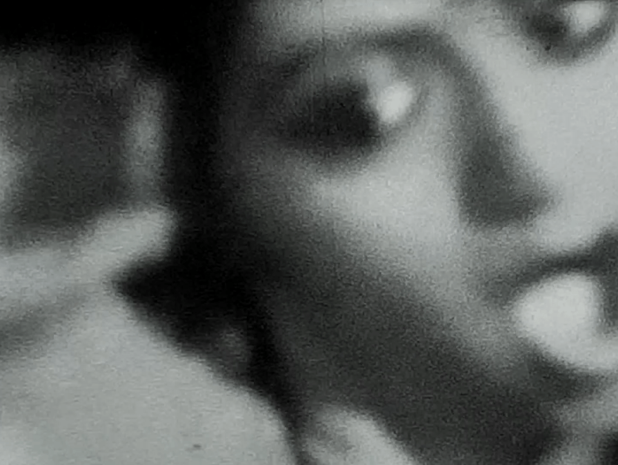 Blurry black and white photo of the face of a person. They have an open mouth and are looking off camera